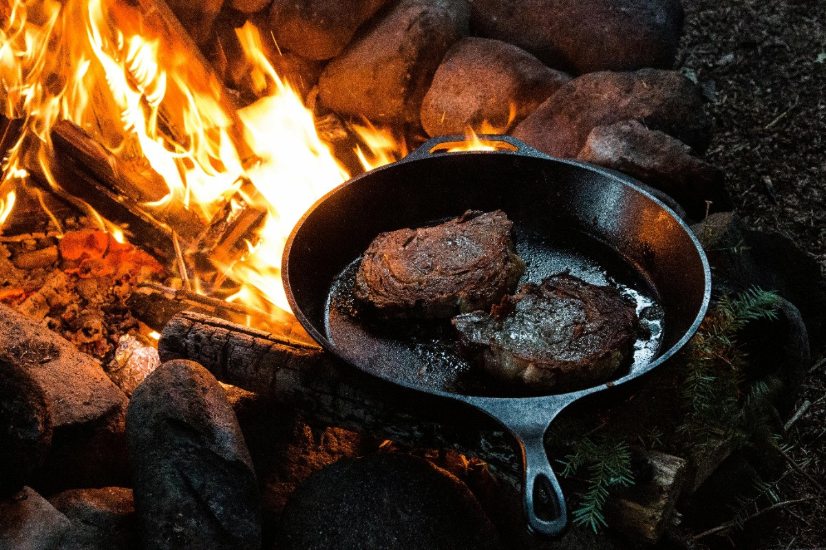 steak cooking on skillet over fire